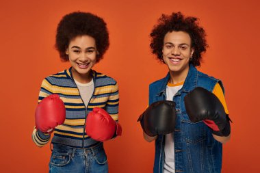 Mutlu Afro-Amerikan kardeşler boks eldivenleriyle turuncu arka planda eğleniyorlar, aile.