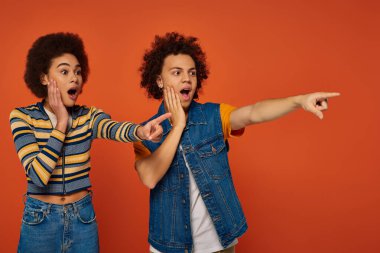Şok olmuş Afro-Amerikan kardeşler günlük kıyafetleriyle bir yeri işaret ediyorlar, aile kavramı.