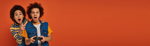 caring african american brother and sister playing video games with joystick, family concept