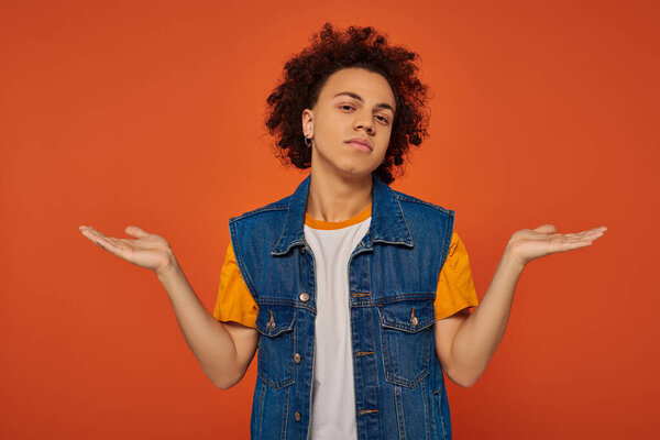 handsome young african american man in casual urban attire posing emotionally on orange background