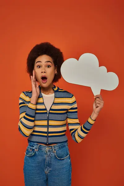 Stock image attractive african american woman in stylish attire posing with thought bubble on orange backdrop