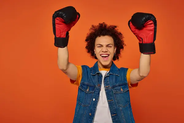 stock image handsome joyous african american man posing actively in boxing gloves on orange background