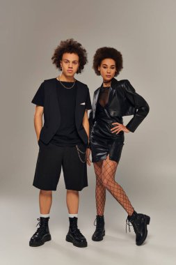 Çekici moda Afrikalı Amerikalı kardeşler şık siyah kıyafetler içinde aktif olarak birlikte poz veriyorlar.