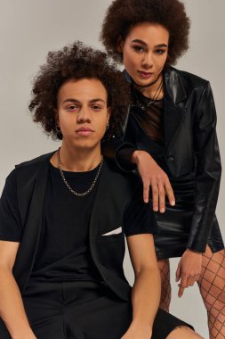 Çekici Afrikalı Amerikalı kardeşler birlikte poz veriyorlar ve gri arka planda oturuyorlar, aile.