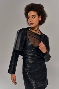 Gri arka planda poz veren şık siyah elbiseli güzel Afro-Amerikan kadın modeller.