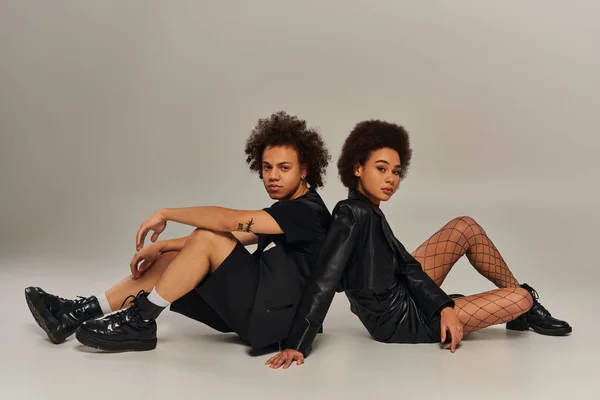 魅力的な若いアフリカ系アメリカ人の兄弟と姉妹で 床に座っているファッショナブルな黒い服装 — ストック写真