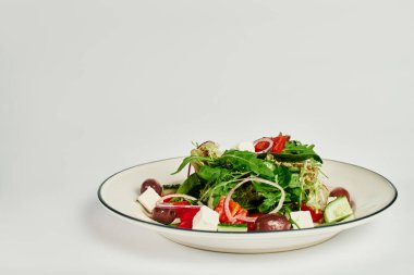 Gri arka planda taze yapılmış lezzetli ve geleneksel Yunan salatası, yemek fotoğrafçılığı.