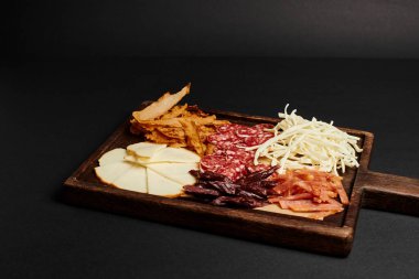 Peynir seçmeli şarküteri tahtası, kurutulmuş sığır eti ve tahta kesme tahtasındaki salam dilimleri.