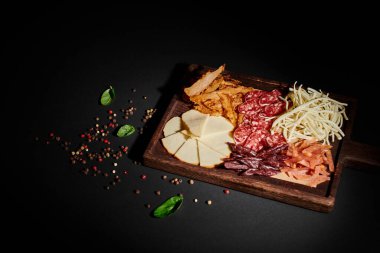 Gurme peynir seçimi, kurutulmuş sığır eti ve salam dilimleriyle şarküteri panosunun yüksek açılı görüntüsü