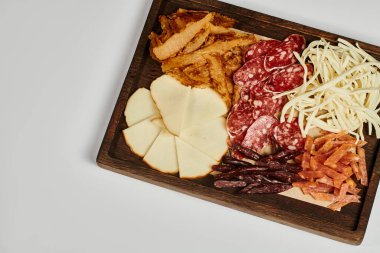 Şarküteri kurulu gurme peynir seçimi, kurutulmuş sığır eti ve salam dilimleri ile gri arka planda