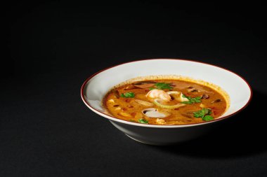 spicy Tom yum soup with coconut milk, shrimp, lemongrass and cilantro on black background. close up clipart
