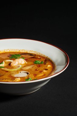 spicy Tom yum soup with coconut milk, shrimp, lemongrass and cilantro on black background, close up clipart