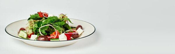 тарелка с вкусным и традиционным греческим салатом на сером фоне, баннер пищевой фотографии