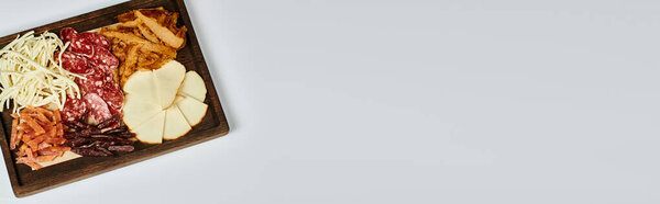 charcuterie board with gourmet cheese selection, dried beef and salami slices on grey banner