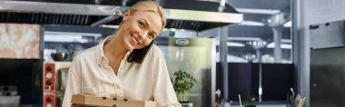 Pizza kutularıyla neşeli bayan menajer akıllı telefondan konuşuyor ve modern kafe, yatay afiş