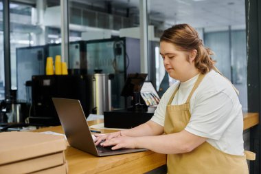 young female employee with mental disability working on laptop on counter in cafe, inclusivity clipart