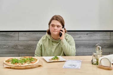 Modern, rahat bir kafede akıllı telefondan konuşan akıl hastası genç bir kadın.