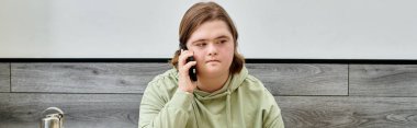 Down sendromlu genç bayan müşteri modern, rahat bir kafede cep telefonuyla konuşuyor.