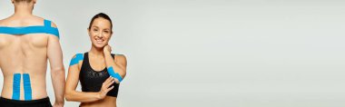 Neşeli kadın ve spor adam vücutlarında kineziyolojik bantlar olan gri arka plan, pankart
