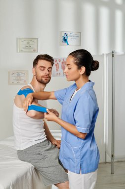Yakışıklı hastasına Kinesio bandı yapıştırıyor. Sağlık sigortası.
