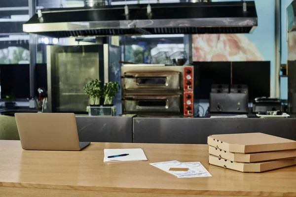 laptop near pizza boxes and menu cards on wooden counter in modern cafe setting, cozy atmosphere