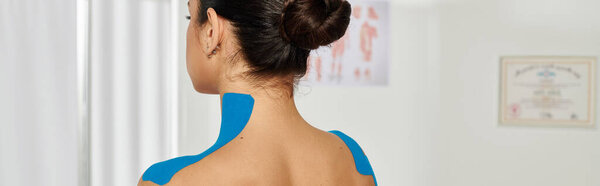 back view of young female patient with kinesio tapes on her neck and shoulders, healthcare, banner