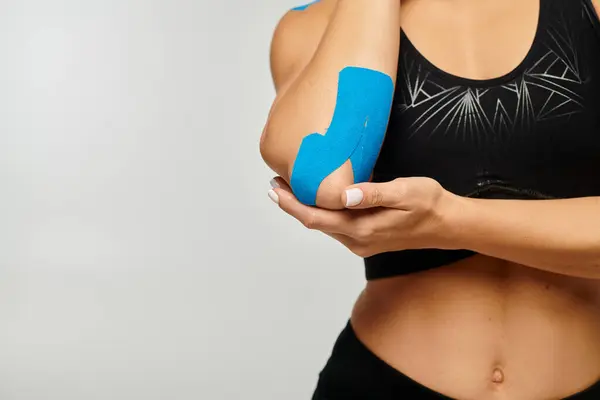 stock image cropped view of young woman in black sport outfit touching kinesiological tapes on her elbow