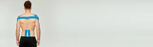 Zadní Pohled Muže Kineziologickými Páskami Zádech Rameni Šedém Pozadí Prapor — Stock fotografie