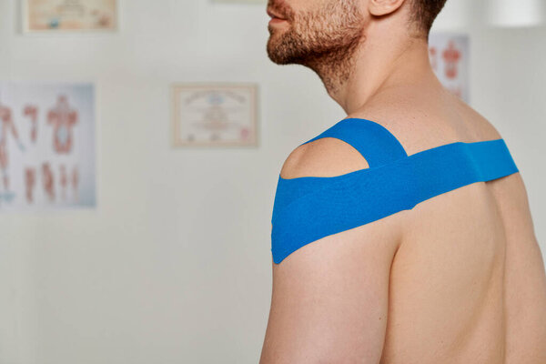 cropped view of man with blue kinesiological tapes on shoulder during appointment, healthcare