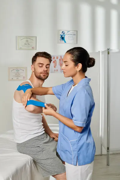 stock image attractive young doctor in medical costume putting kinesio tape on her handsome patient, healthcare