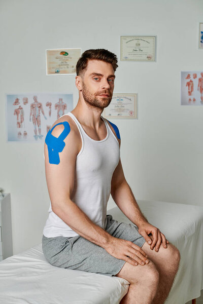 good looking bearded man with kinesiological tapes sitting and looking at camera, healthcare