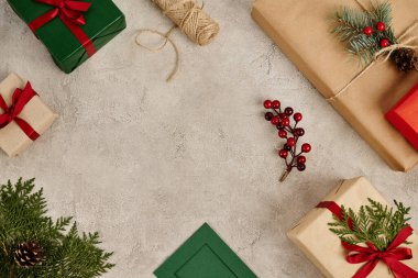 Kırmızı kurdeleli ve çam dallı hediyeler gri desenli arkaplanda kutsal üzümler, Noel.
