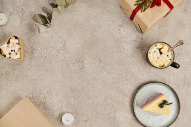 Gri desenli yüzeyde Noel hediyeleri, puding ve kremalı sıcak çikolata olan çerçeve