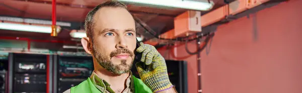 stock image concentrated technician in safety clothes talking by phone and looking away, data center, banner