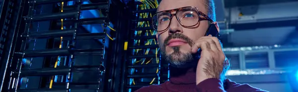 stock image good looking concentrated specialist in turtleneck talking by phone during work, data center