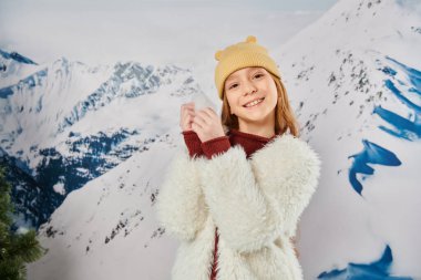 Ergenlik öncesi tatlı kız ellerinde karla kameraya, modaya ve modaya neşeyle gülümsüyor.