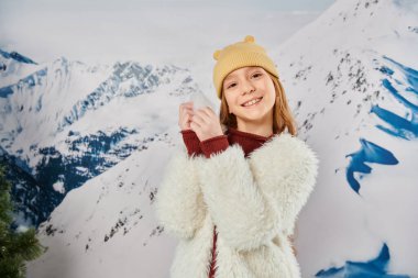 preadolescent cute girl with snow in hands smiling cheerfully at camera, fashion and style clipart