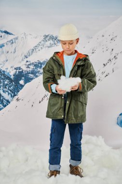vertical shot of little boy with  snow in hands wearing stylish warm outfit, fashion clipart