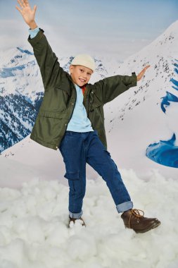 Neşeli küçük çocuk, eğleniyor ve gülümsüyor. Dağ zemininde hareketli poz veriyor. Moda.