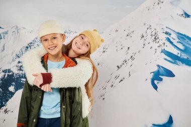 joyous friends in stylish winter attire hugging each other with mountain background, fashion concept clipart