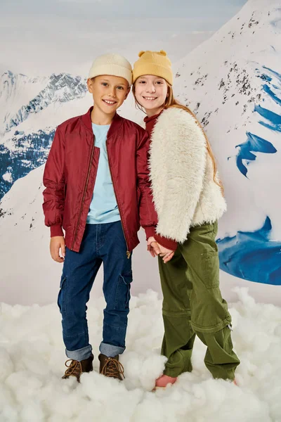 stock image vertical shot of jolly preadolescent friends in stylish clothes smiling at camera and holding hands