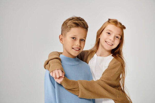 happy preteen boy and girl in casual winter clothes hugging and smiling at camera, fashion concept