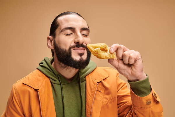 joyful man smelling honey baklava  on beige background, traditional middle eastern dessert