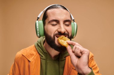 Kulaklıklı neşeli bir adam bej arka planda bal baklavası yiyor, Türkçe zevkler