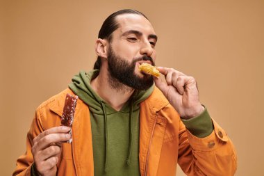 arabic bearded man and biting baklava and holding cevizli sucuk on beige backdrop, turkish delights clipart