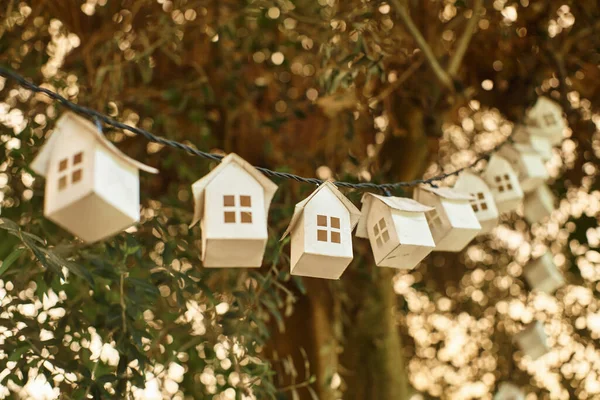 stock image eco-friendly garland made of wooden houses on green tree with fresh foliage inside of greenhouse