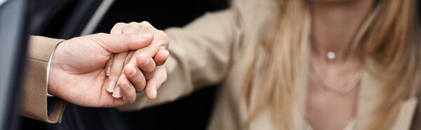 обрезанный вид мужчины, держащего за руку элегантную женщину в формальной одежде, выходящую из машины, баннер