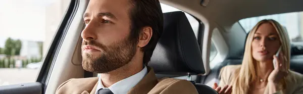 stock image elegant man in suit driving luxury car with blonde businesswoman talking on smartphone, banner