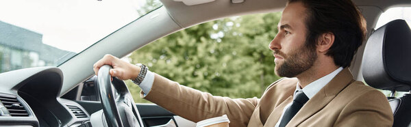 бородатый бизнесмен в бежевом костюме с выпивкой на вынос и вождение автомобиля на городской улице, баннер