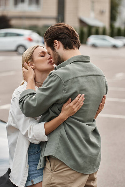 romantic couple in stylish casual clothes embracing while standing on urban street, love story